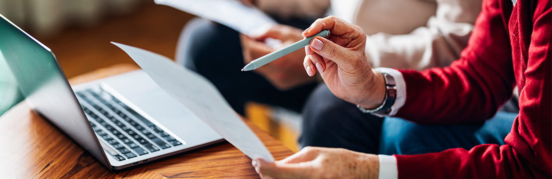 Individuals reviewing financial paperwork and online account information as part of year-end tax planning.